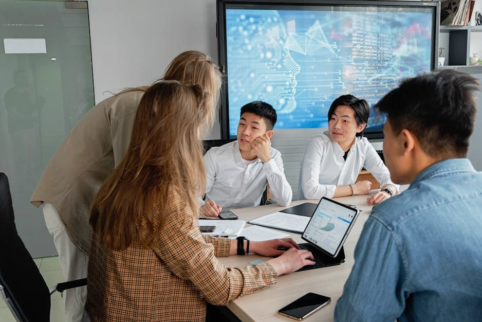 A modern office meeting room with a presentation on sustainability metrics on a large screen.